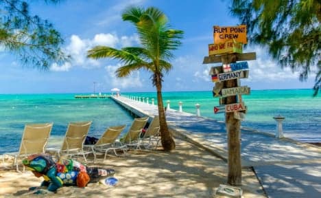 Rum Point. The pier extending out into turquoise water, painted starfish sculpture on the sand, lounge chairs under the palms.