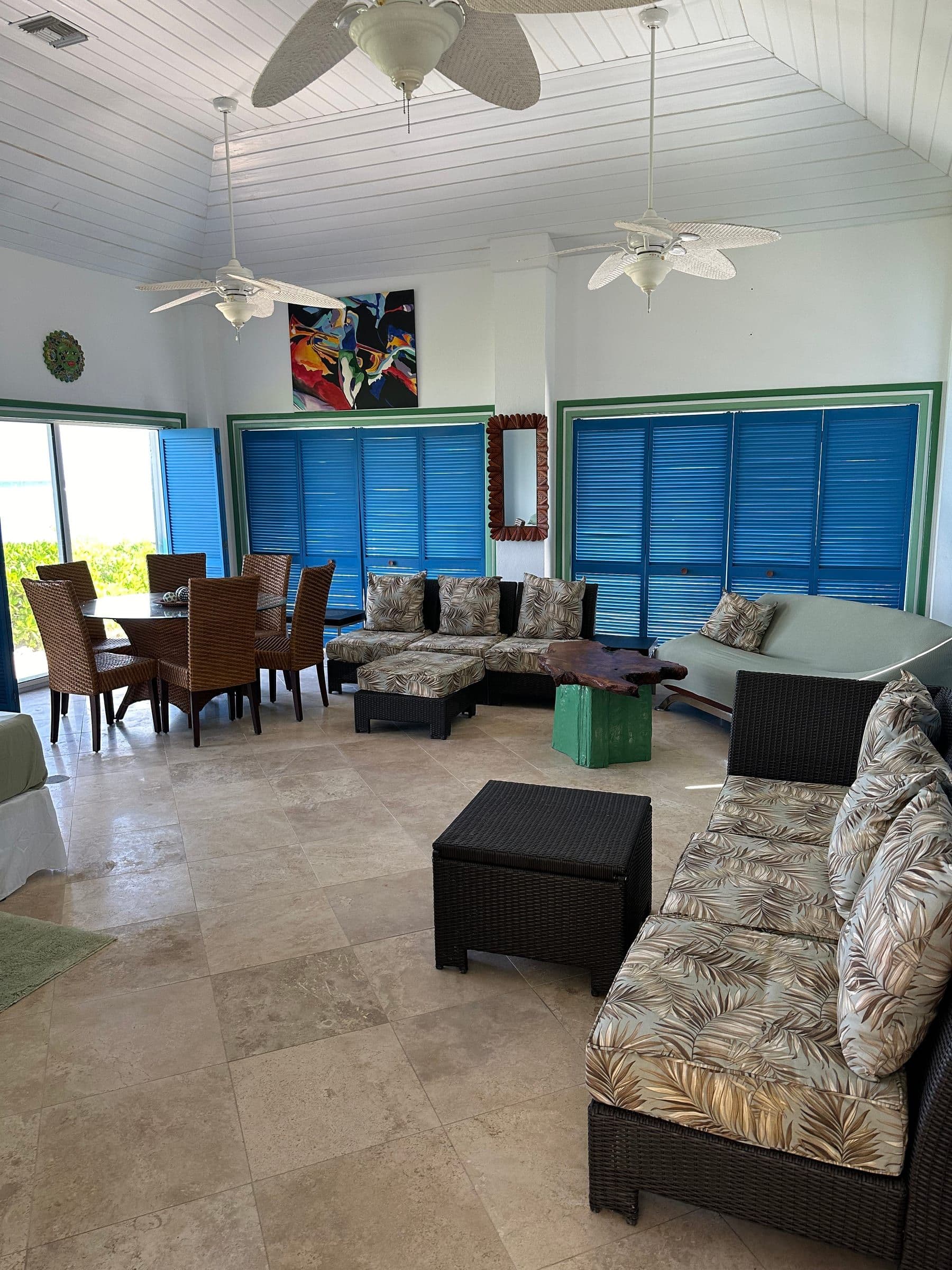 Inside the cottage. Vaulted ceiling, blue louvered shutters, dining table and sectional.