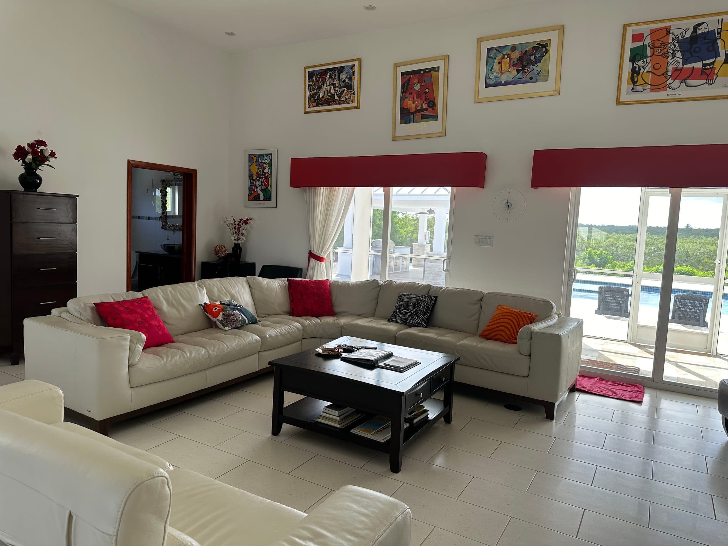 The great room. Beige sectional, framed art, sliding doors open to the pool deck and ocean.